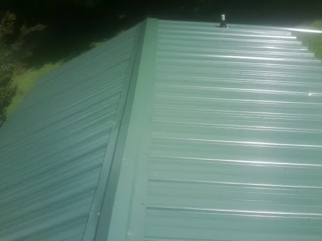 New green metal panels meeting at the ridge of a roof — Flat Roof Repair work by our crew in Flintstone
