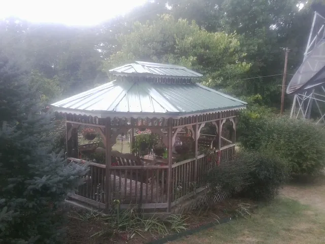 Green metal roof on a backyard gazebo surrounded by garden beds in Flintstone