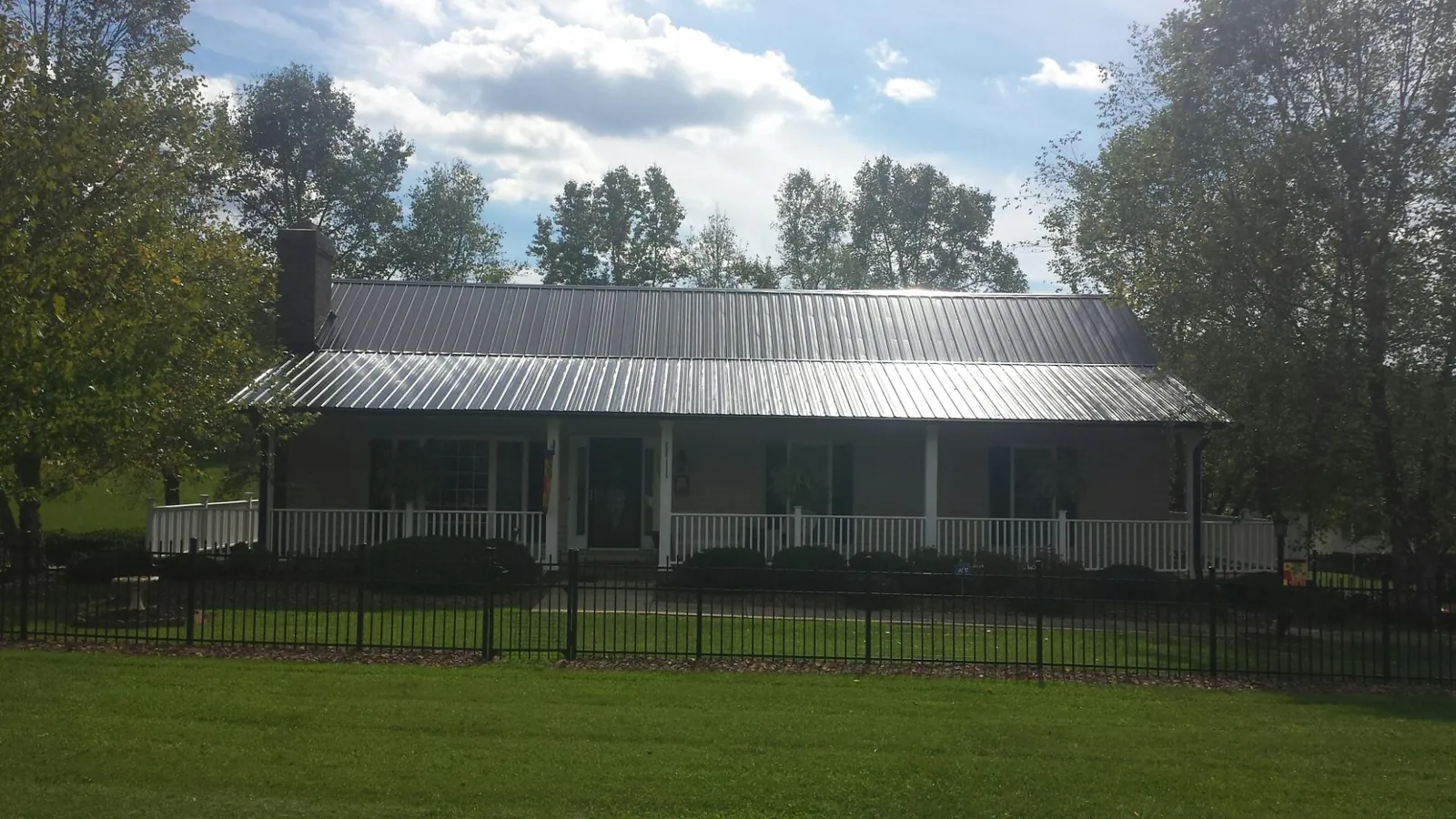 Gray metal roof on a brick ranch with a full width front porch — Gutter Guard Installation work by our crew in Flintstone