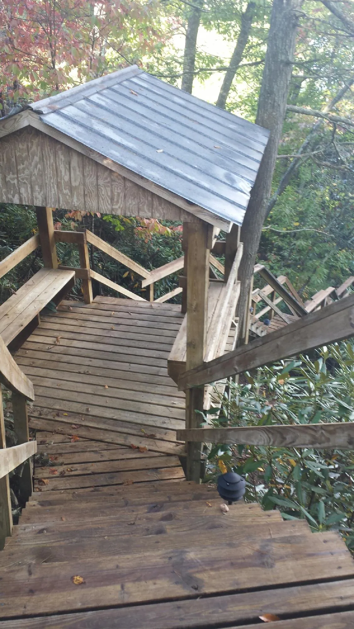 Metal roofed shelter over wooden steps on a wooded walkway — Skylight Repair & Installation work by our crew in Flintstone