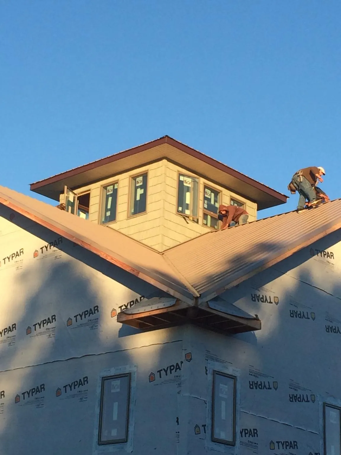 Roofers working around a rooftop cupola on a new metal roof at sunset — Roof Waterproofing in Flintstone by Roofing Brothers